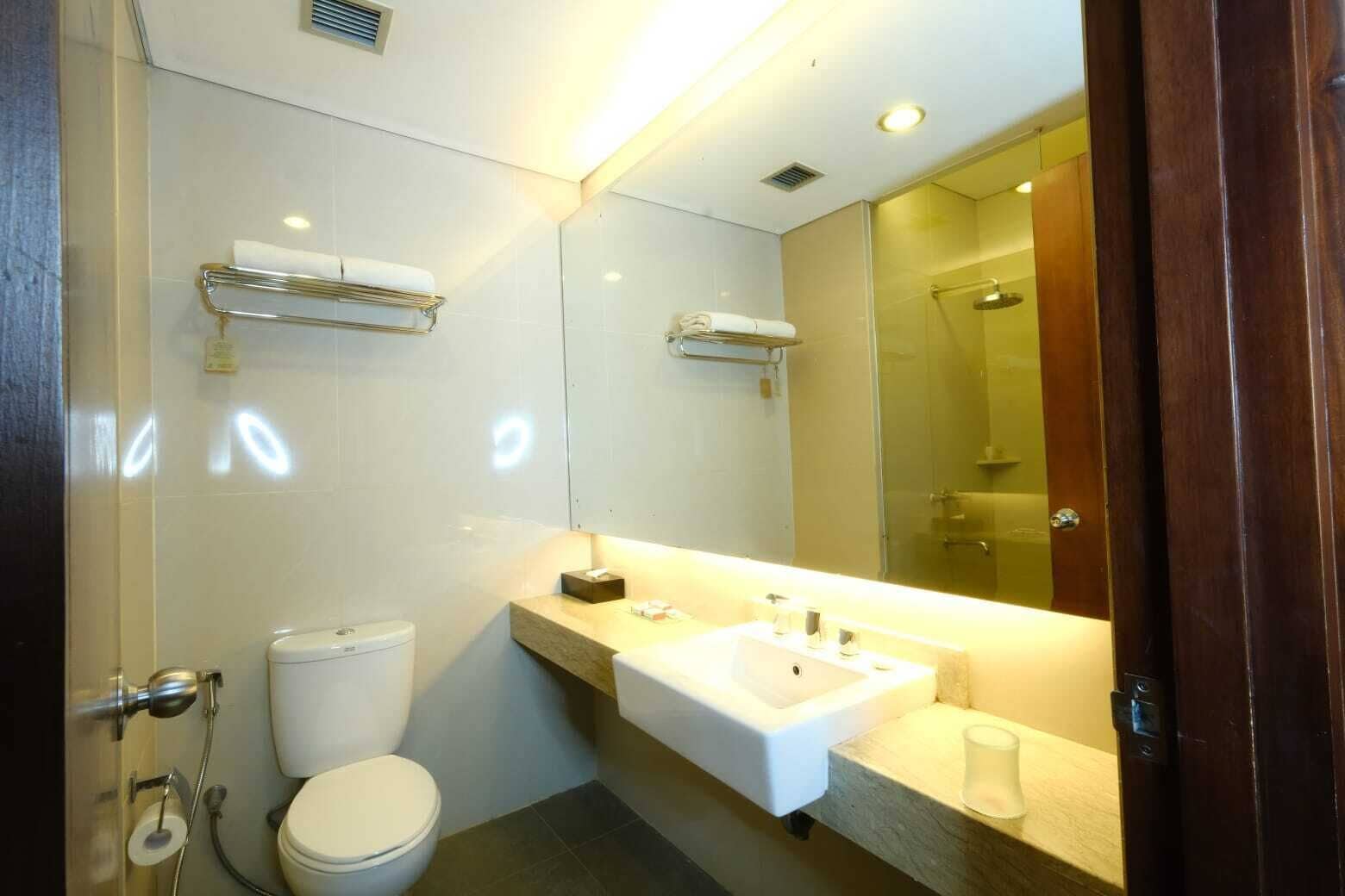 A modern bathroom with a white sink, a toilet, a glass shower enclosure, and a large mirror.
