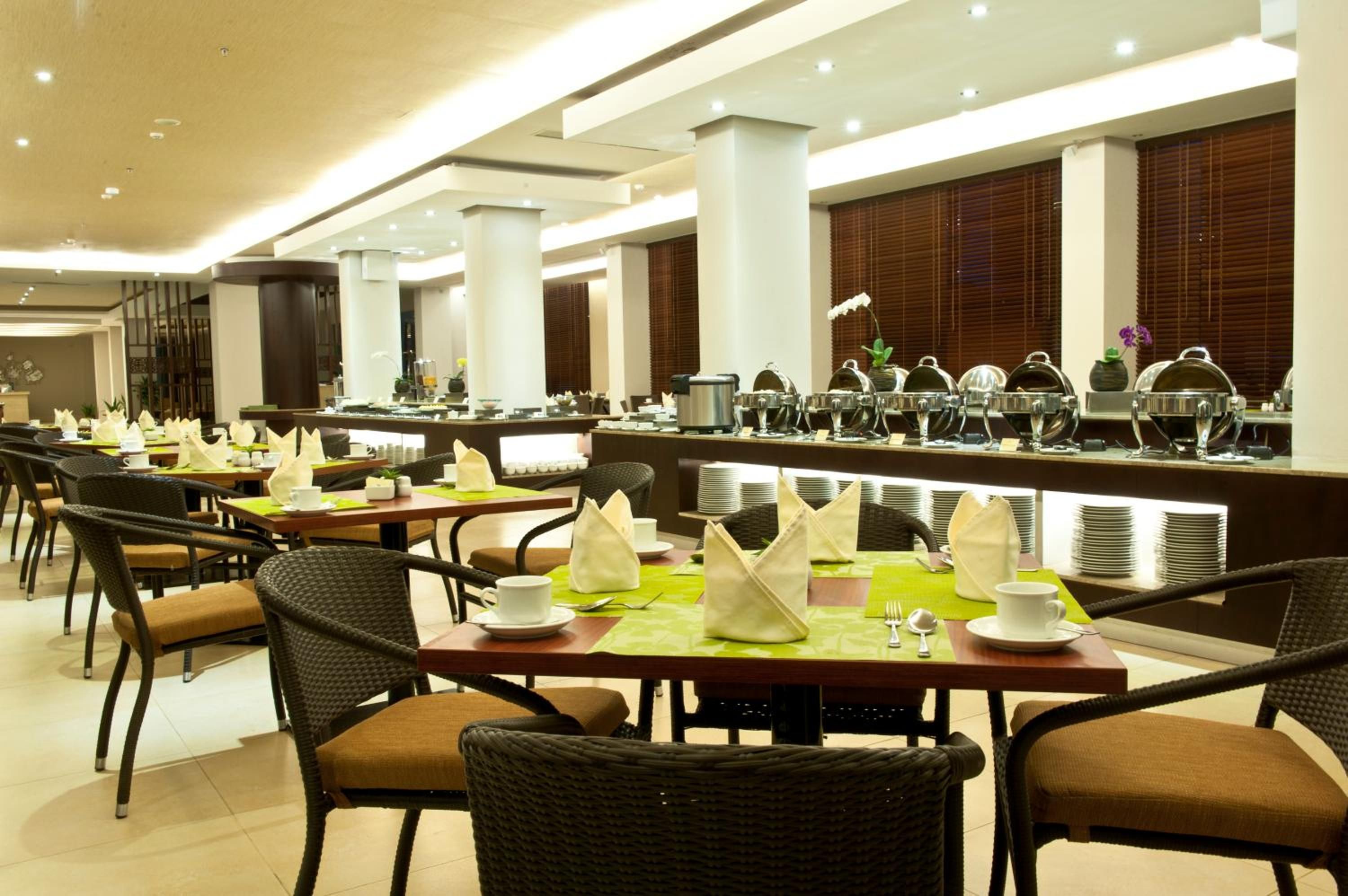 Un comedor de hotel con varias mesas, sillas y una barra de buffet.