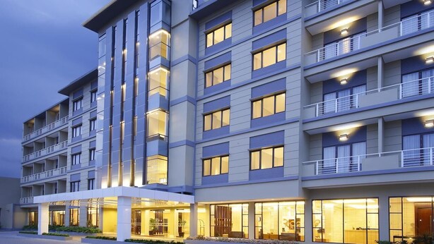 A multi-story hotel with a modern design, featuring balconies on each floor and a well-lit entrance area. - Hotel Surya Yudha Purwokerto (Purwokerto)