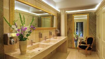 Relax in this serene bathroom with a long countertop, two sinks, a large mirror, and a potted plant.