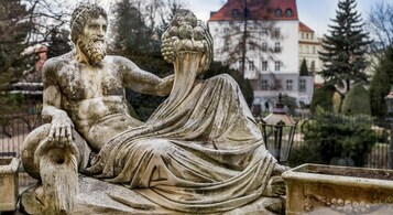 Una estatua de piedra que muestra a un hombre y una mujer sentados en un parque.