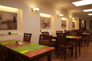 A dining area with multiple tables and chairs, wall-mounted light fixtures, and artwork. - Kobza Haus Old Town (Gdansk)