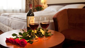 Hotelkamer met een bed, nachtkastje met een fles Chianti wijn, twee wijnglazen en een rozenboeket.
