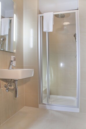 Eenpersoonskamer | Badkamer | Een douche, een haardroger, handdoeken, zeep