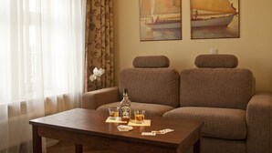 Een kamer met twee banken, een houten salontafel en een fles Jack Daniel's whisky. Twee schilderijen aan de muur beelden zeilboten af.