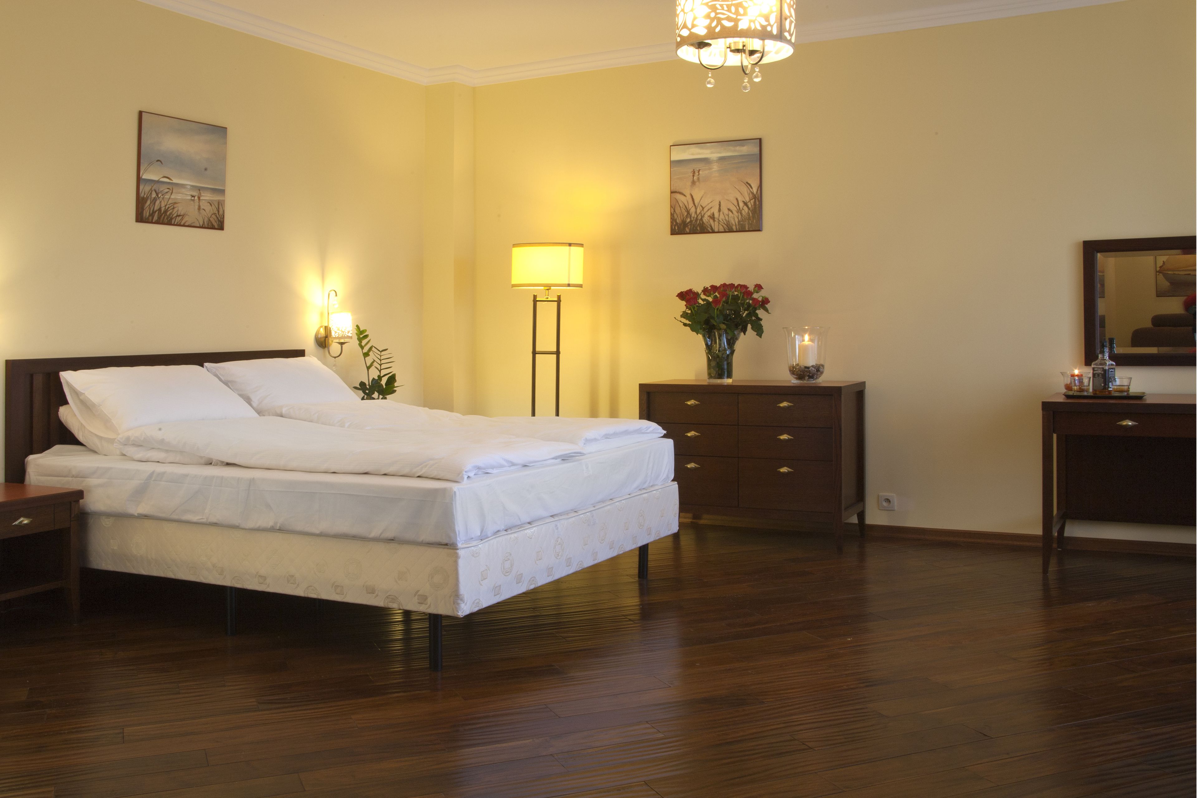 Une chambre à coucher comprenant un lit, des tables de chevet, une commode, un miroir et des lampes fixées au mur.
