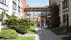 Een binnentuin met een pad, banken en groen.
