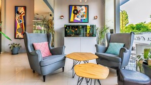 A modern interior with two grey armchairs, a wooden coffee table, and a fish tank. - Art Hotel Simona (Sofia)