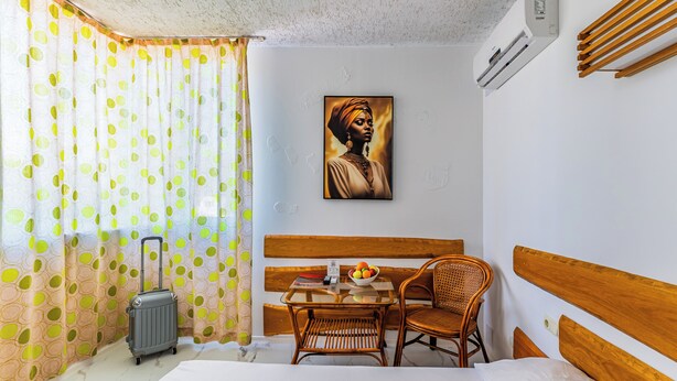 A hotel room with a bed, a table with a bowl of fruit, a suitcase, and a chair. - Art Hotel Simona (Sofia)