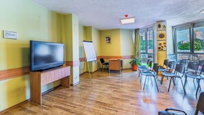 A conference room with a flat-screen TV, whiteboard, and chairs. - Art Hotel Simona (Sofia)