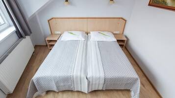 Una cama de matrimonio con dosel de madera, una mesita de noche y una ventana con cortinas.