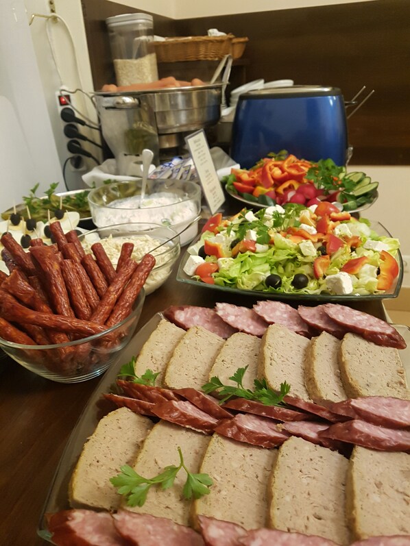 A buffet table with various food items including sausages, sliced meats, and a salad. - Antica Residence (Kraków)