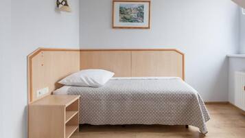 Uma cama de solteiro com cabeceira de madeira, mesa de cabeceira e luminária na parede.