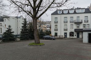 Et boligområde med en asfalteret gårdsplads, et træ og en parkeret bil.