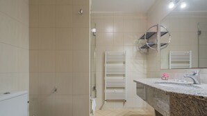 A bathroom with a toilet, a shower, and a sink with a marble countertop. - Antica Residence (Kraków)