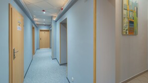 Um corredor com portas, carpete claro e teto com iluminação embutida.