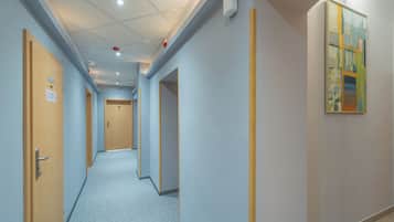 A hallway with doors, a ceiling with recessed lighting, and a painting on the wall.