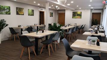 Un salón de conferencias con varias mesas y sillas, suelo de madera y obras de arte colgadas en la pared.