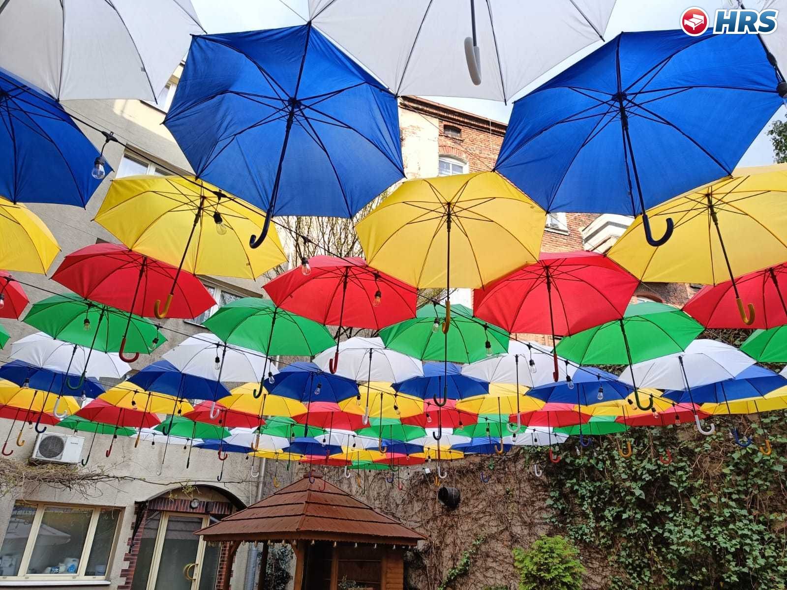 Fachada de edificio con sombrillas de colores colgando.