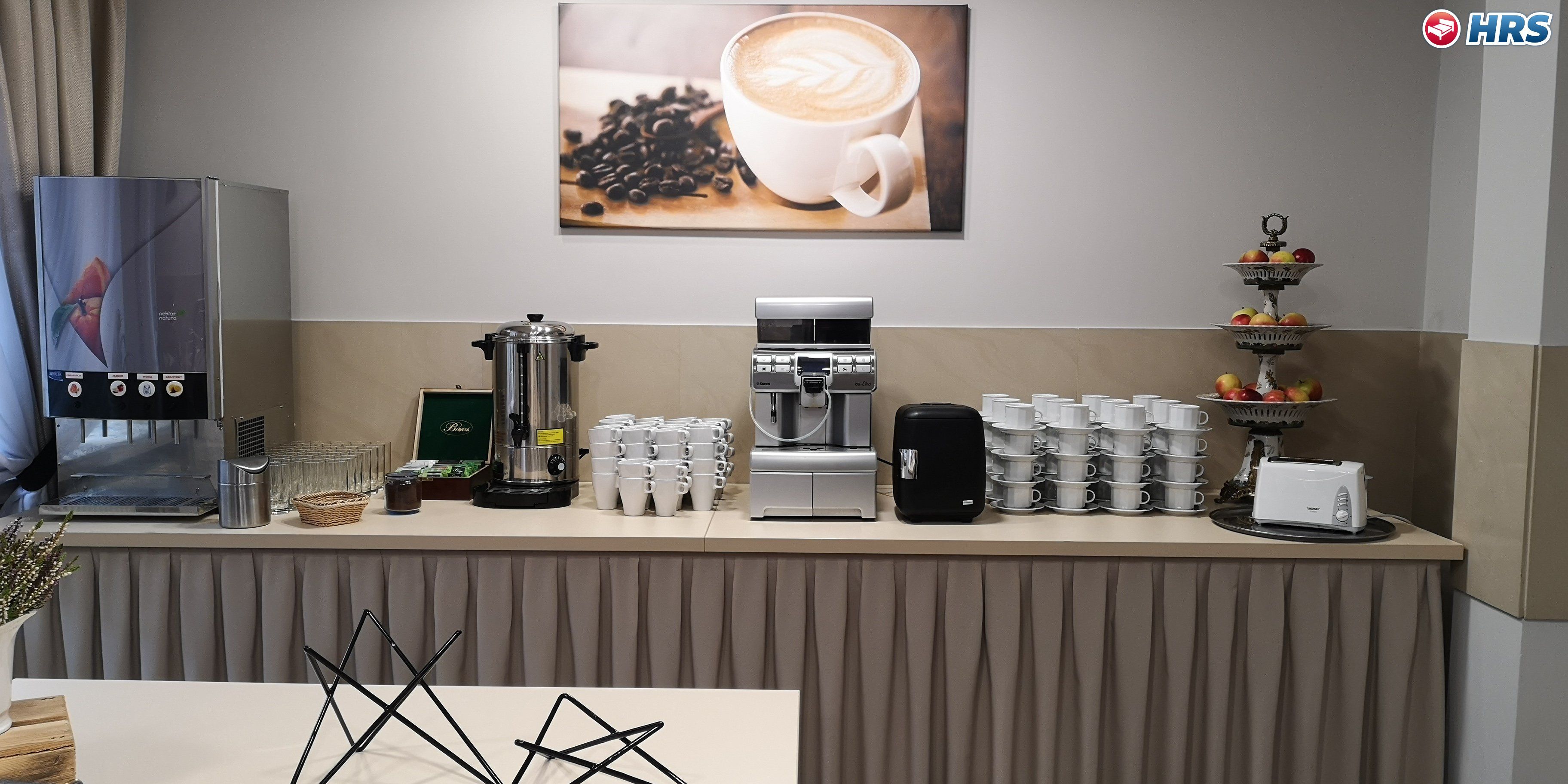 Una estación de café con una máquina de café, un molinillo y una selección de tazas de café.