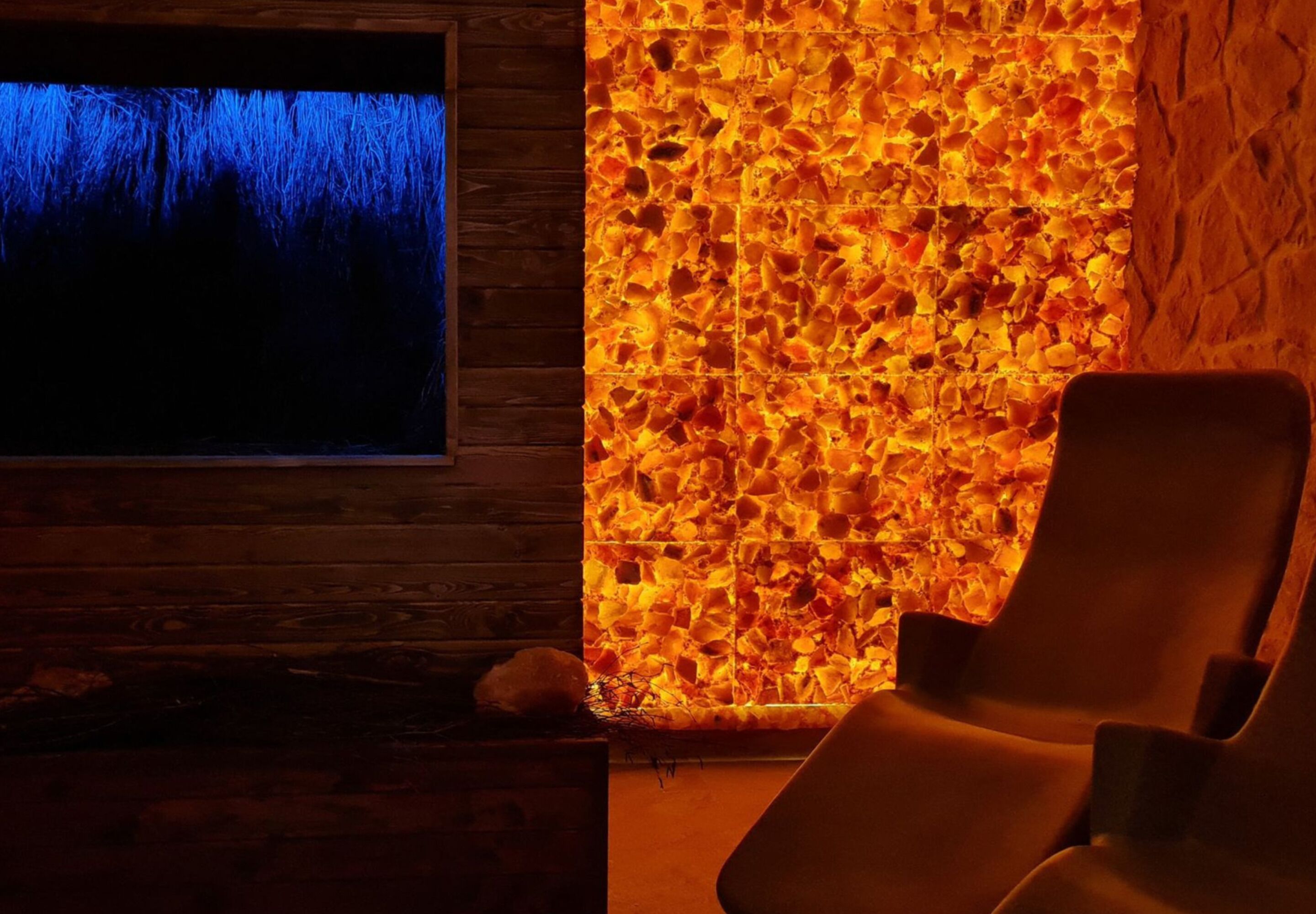 Una spa con parete in legno, parete in pietra con motivo a mosaico e una poltrona reclinabile.