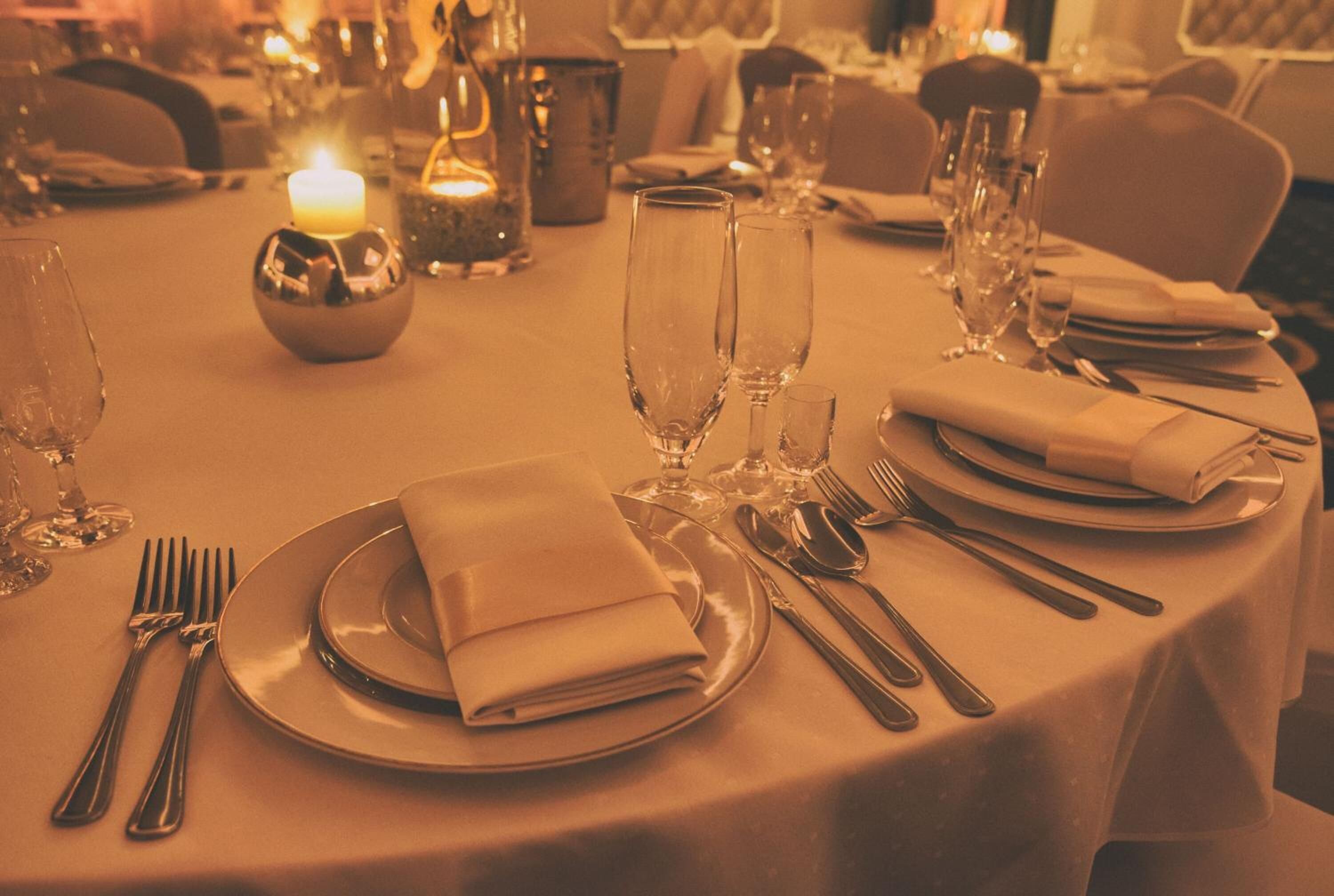 A table set for a meal with plates, cutlery, and glasses, a candle, and a decorative bowl.
