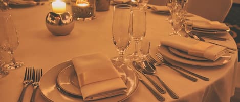 A table set for a meal with plates, cutlery, and glasses, a candle, and a decorative bowl.