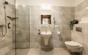 A modern bathroom with a glass-enclosed shower, a pedestal sink, a toilet, and a mirror above the sink.
