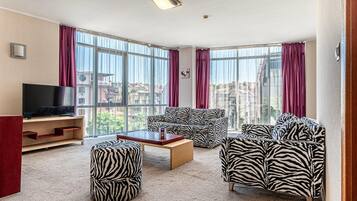 A modern living room with a large window, a flat-screen TV, and zebra-patterned furniture.