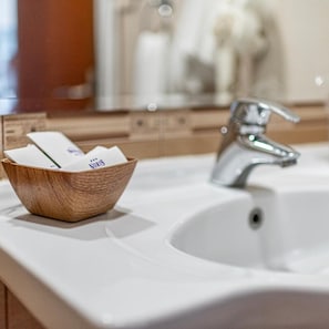 A bathroom with a wooden bowl containing toiletries, a white sink, and a chrome faucet. - Noris Hotel Plovdiv (Plovdiv)