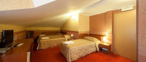 Een hotelkamer met twee bedden, een bureau met een televisie en een rode vloerbedekking.