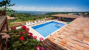 Une piscine sur le toit offrant une vue dégagée sur le paysage environnant, notamment sur les collines lointaines et une ville.