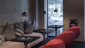 A modern interior with a sofa, red chairs, a small table, and pendant lights.