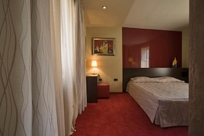 A hotel room with a bed, a nightstand, a lamp, and a painting on the wall.