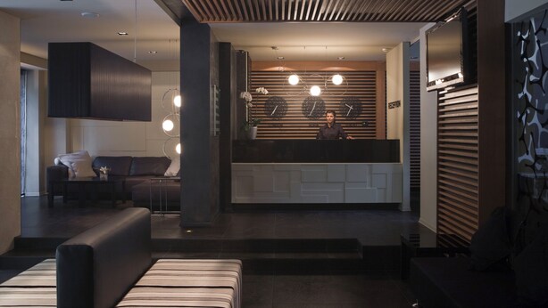 A modern interior with a reception desk, seating area, and a kitchen.