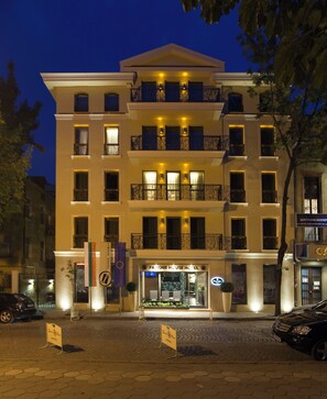 A multi-story hotel with a central entrance, balconies, and a sign indicating it is a hotel.