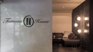 A lobby with a sign reading 'Famous House,' a leather sofa, a coffee table, and a wall-mounted light fixture.