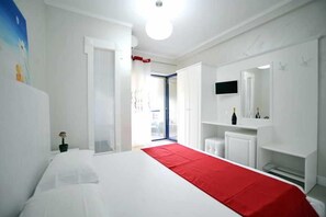 A hotel room with a large bed, a television, a mirror, and a red accent on the bedspread. - Iliria International (Durrës)