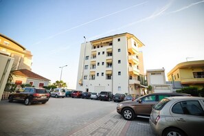A multi-story residential building with a parking lot in front. - Iliria International (Durrës)