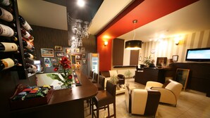 A modern hotel lobby with a bar area, seating, and a television. - Hotel Seven 7 (Kalisz)