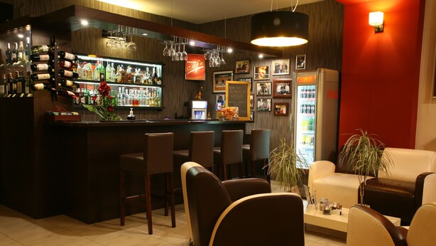 A bar area with a wine rack, seating, and a Coca-Cola refrigerator. - Hotel Seven 7 (Kalisz)