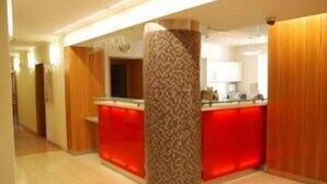 A hotel lobby with a reception desk, a patterned column, and wooden paneling.