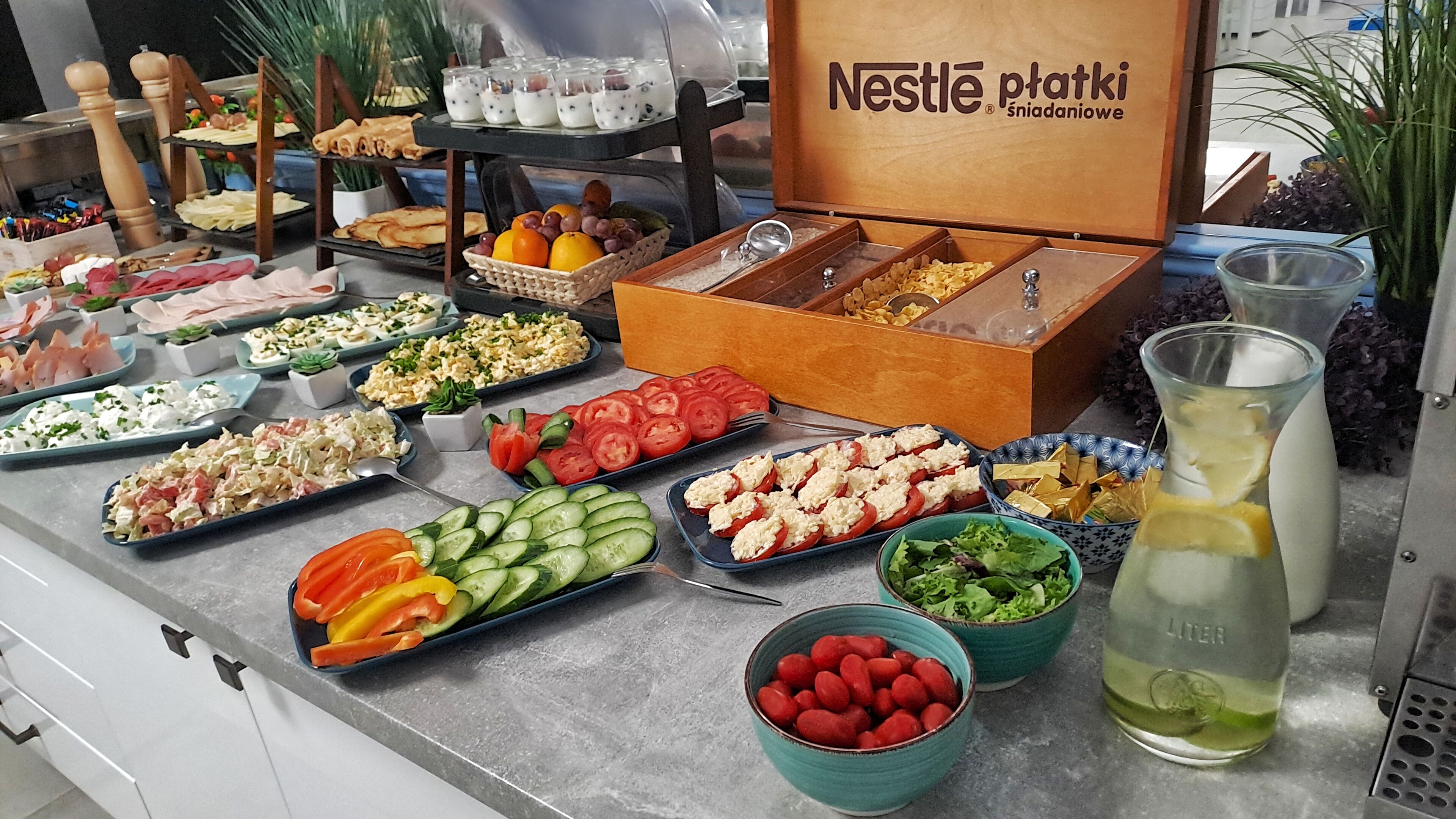 Un buffet con diversi cibi, tra cui insalate, frutta e un cartello Nestlé ptaki.