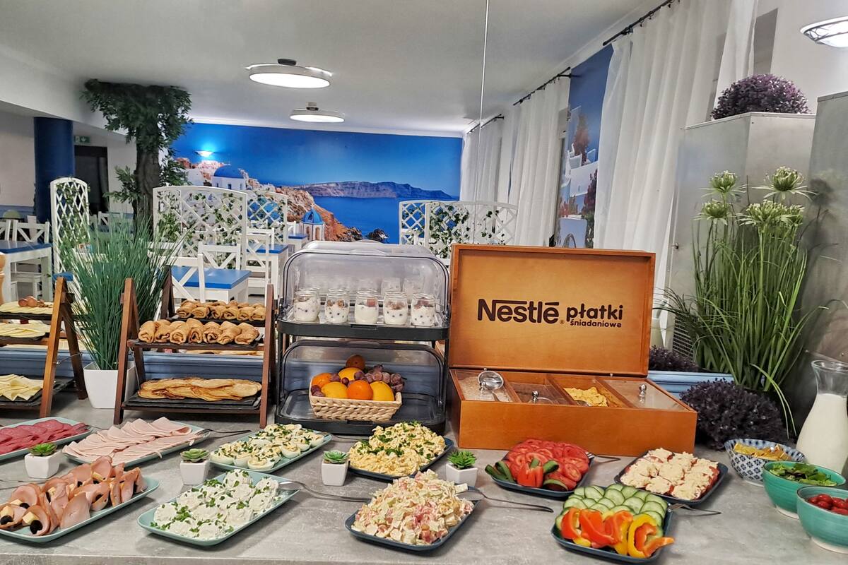Un buffet proposant une variété de plats, un présentoir de produits Nestlé P'tatki et un décor pittoresque en arrière-plan.