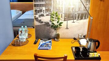 A hotel room with a desk, chair, and a large wall mural of a historic building.