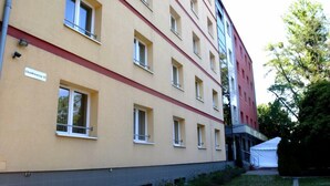 A multi-story building with a beige facade and red accents. There is a sign indicating the building's name or address.