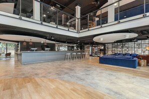 Un interno moderno con angolo bar, posti a sedere e soffitto alto con travi a vista.