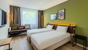 A hotel room with two beds, a seating area, and artwork on the wall. - Campanile Warszawa Polnoc (Warsaw)