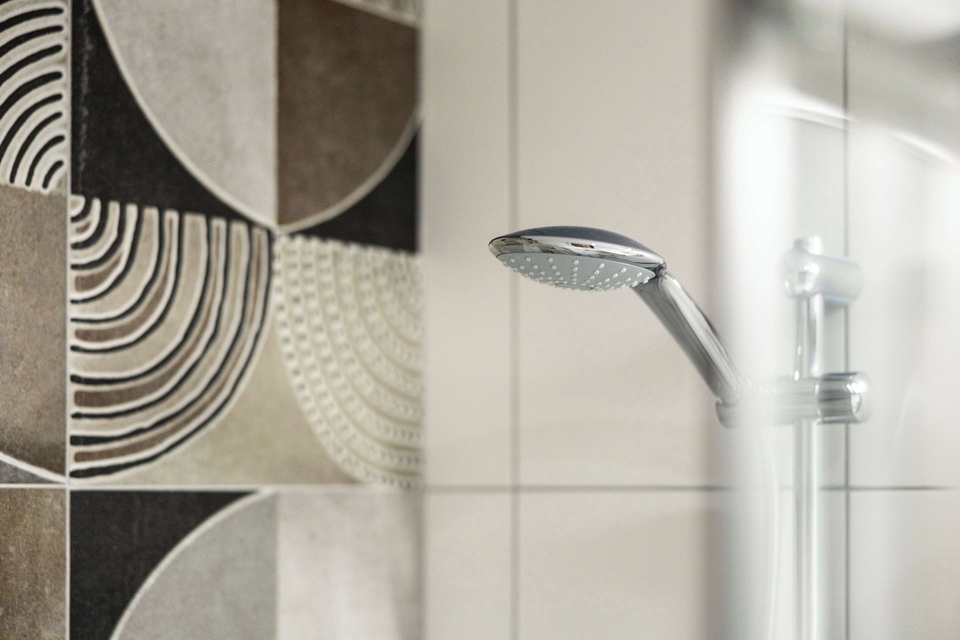 A showerhead with a curved design, mounted on a clear glass enclosure.