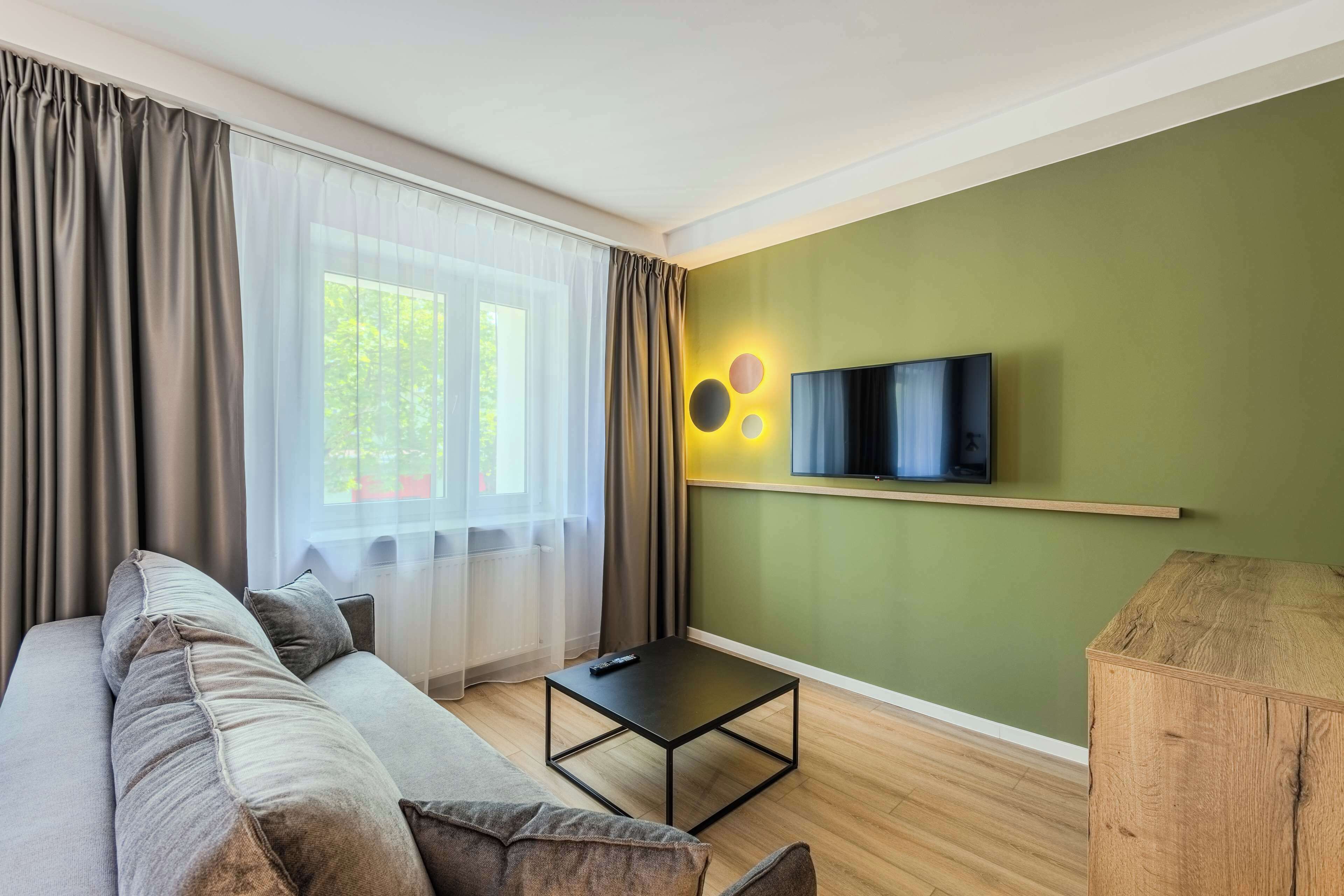 Una sala de estar moderna con un sofá, una mesa de centro y un televisor montado en la pared.